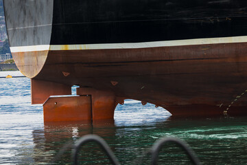 Close-up of ship hull and rudder under waterline, industrial marine detail with propeller area and steel structure, maritime engineering and shipping concept, port infrastructure and vessel design © Design