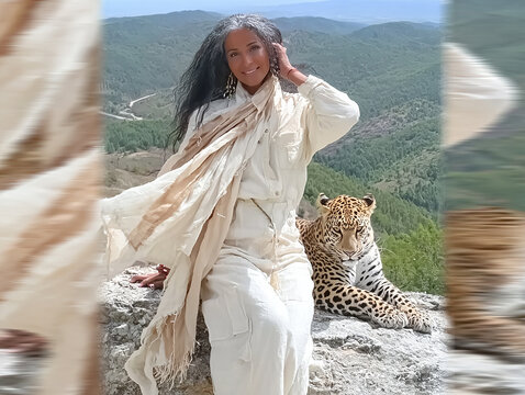 Woman posing with leopard on mountain peak