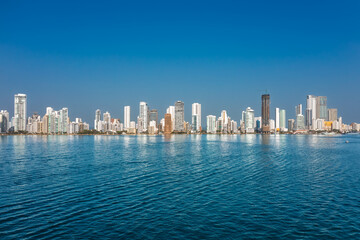 Obraz premium Panoramic view of the Cartagena skyline and Bocagrande district with modern skyscrapers reflecting on the water under a blue sky, Colombia