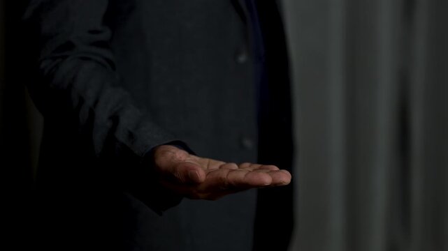 Close up of a businessman in a formal suit showing an open hand, ideal for placing digital holograms or virtual interface elements. Concept of future technology, innovation, business presentation, cop