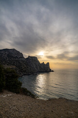 Fototapeta premium Seascape sunset rocks dramatic golden light reflecting on the water along the mountainous coastline