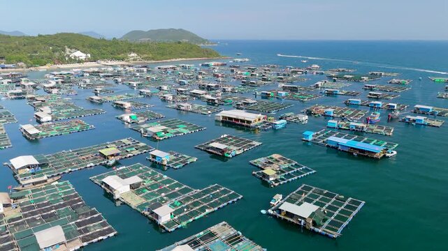 An aerial view of marine farm facilities, including cages for raising marine animals for food. A view of a fishing village, the landscape, and the coastline of a tropical island