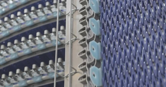 A multi-tiered spiral conveyor in operation, plastic mesh belts moving in different directions. A working transport system with an axisless spiral. Close-up handheld indoors shot, real time speed.