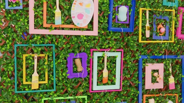 Colorful picture frames and paintbrushes on green garden lattice