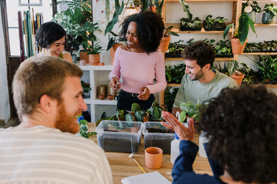 Diverse group of young hispanic people in gardening and planting in a plant care class together in plant shop. Multicultural and multiethnic friends in replanting and horticulture workshop