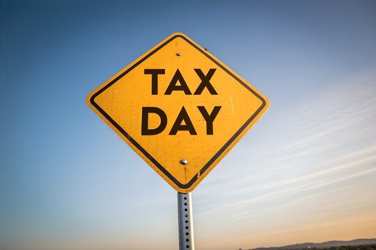 Yellow diamond shaped tax day warning sign on a pole