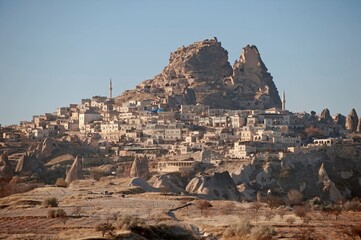 Ancient Uchisar Castle and cave dwellings in Cappadocia, Turkey. Panoramic view of the historic town carved into volcanic rocks under a clear sky. Famous UNESCO World Heritage site  © AAUB
