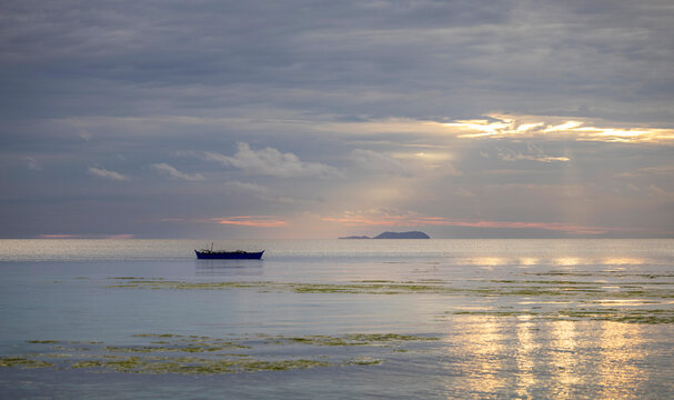 dramatic sunset before storm on the beach with small boat, islands on the horizon, Siquijor, the Philippines