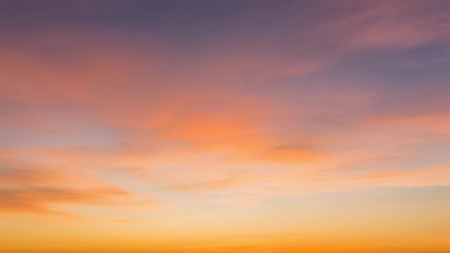 Vibrant sunset sky with soft, wispy clouds painted in hues of orange, pink, and purple.