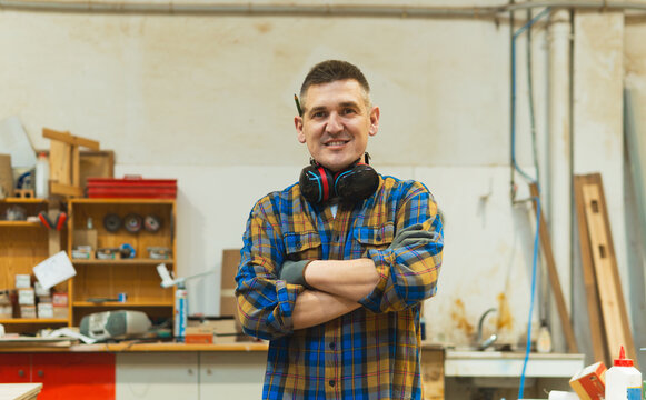 Carpenter man smiling with arms crossed in workshop