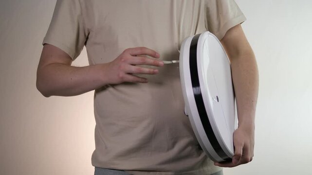 Keep your smart home running smoothly. A person performs routine maintenance on a robotic vacuum cleaner. Ideal for videos about home automation, cleaning routines, and device care. Boost your sales