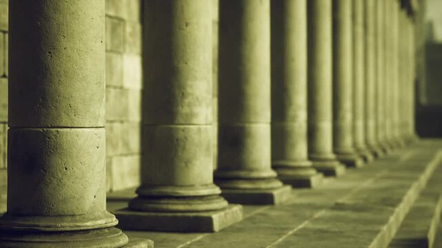 Lowangle pillars Alexandria with moody shadows and repeating rhythm, long corridor of columns, worn stone floor, atmospheric vintage toning.