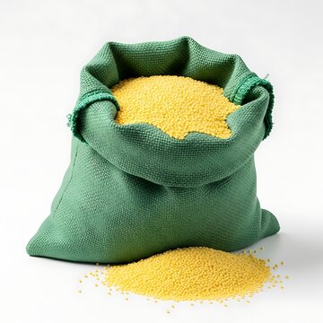 A green bag filled with yellow grains spills some on the surface
