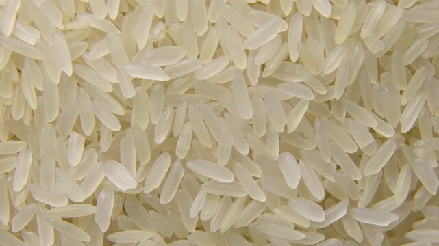 Extreme close-up of high-quality raw white long-grain rice rotating slowly. Perfect for food industry, healthy eating, and agricultural concepts.