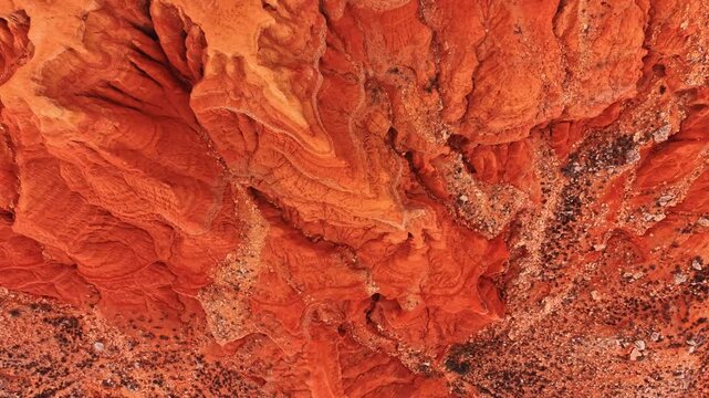 Abstract aerial view of red clay soil erosion patterns. High angle shot of natural textures and deep erosion channels in red earth and rock formations.