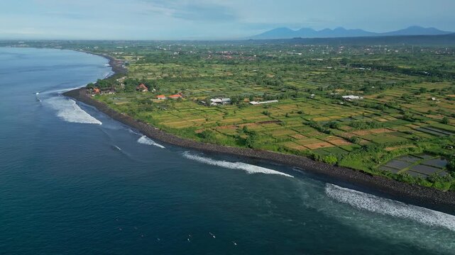 Wide aerial bay panorama with calm surf, green hinterland and distant volcanic silhouettes sweeping drone footage for tourism campaigns, coastal conservation visuals and serene,Bali island,Indonesia