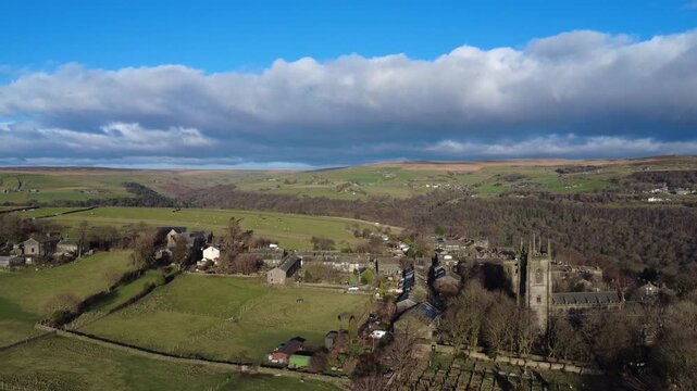 Aerial drone view of the village of heptonstall showing the church graveyard and houses surrounded by the calder valley and west yorkshire landscape