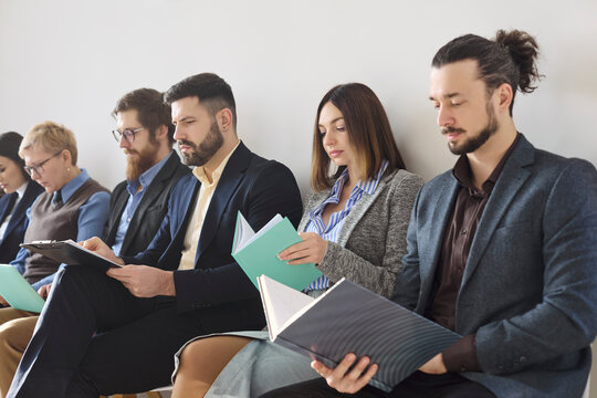 Applicants candidates waiting for interview with resumes. Professionals in attire review folders as HR team manages recruitment and hiring in an office. Clear concept of teamwork readiness.