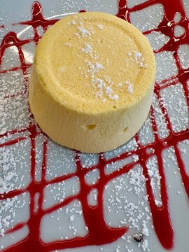 Mini sponge cake with berry sauce and icing sugar, top view
