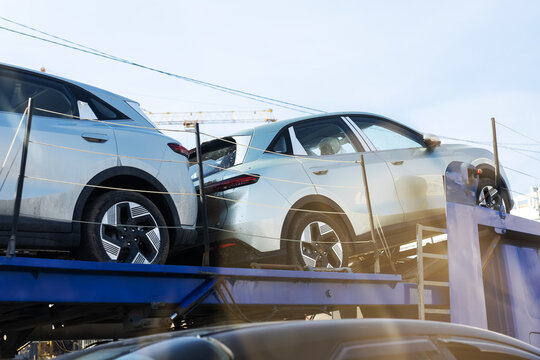 Shiny silver sports utility vehicles arranged on carrier truck in open freight yard