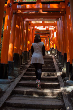 Young Woman Walking Through Vermilion Torii Gates at Fushimi Inari Shrine in Kyoto, Japan