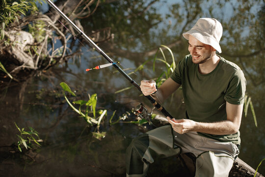 Young fisherman with fishing rod near the lake at summer