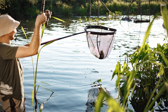 Young fisherman with fishing rod and a net near the lake at summer