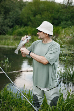 Fisherman with fishing rod near the lake at summer