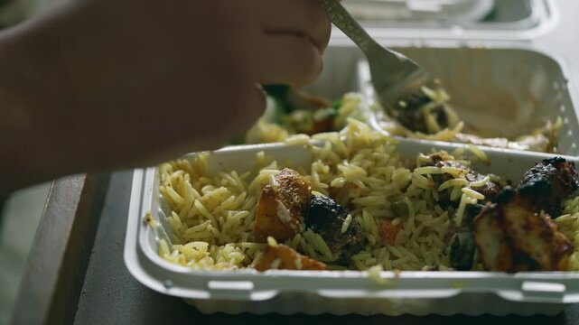 Man eating a takeaway meal of rice and kebab at home