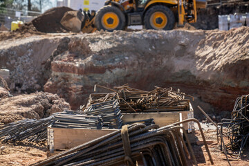 Fototapeta premium Reinforcement steel bundles at active excavation area with heavy machine behind, reflecting groundwork operations, material supply, and build workflow