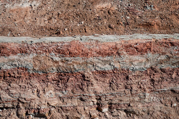 Fototapeta premium Exposed stratified soil wall in excavation cut, illustrating geological layers, ground analysis, and civil engineering site assessment needs