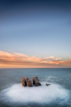 Urro del Manzano rock formation in Liencres at sunset with long exposure silk effect on the ocean