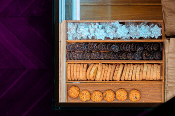 Assorted cookies bakery counter food retail place top view frame work in a wooden tray on a purple background with a glass top