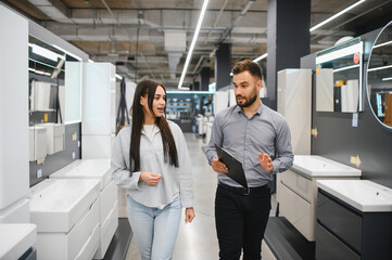 Sales assistant helping female customer choosing bathroom furniture
