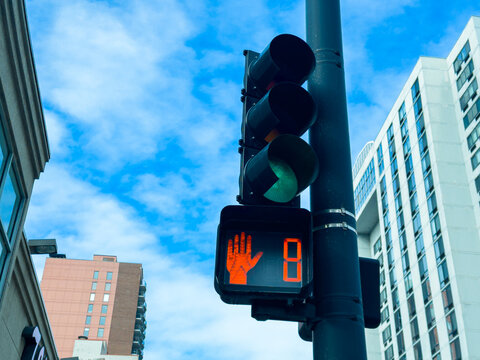 Traffic signal shows stop sign with countdown timer in urban setting during daytime