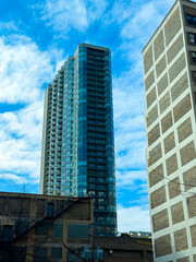 Obraz premium High-rise buildings stand against a blue sky with clouds in an urban setting during daytime in a city location