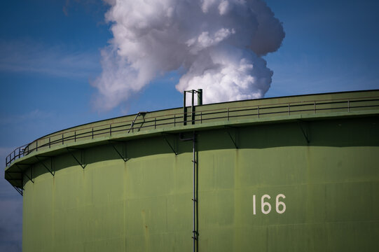 Aboveground Petroleum Storage Tank with a steam cloud behind at a refinery in Washington state. These tanks are large containers that rest on the ground&rsquo;s surface commonly used for substances like oil