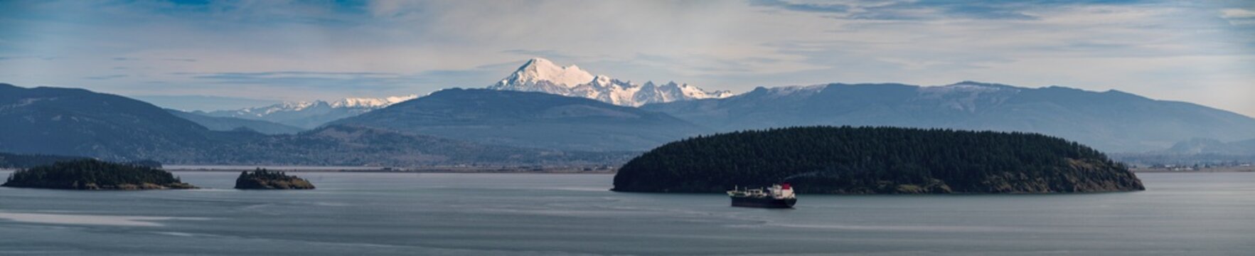 Panoramic view of an Oil Tanker anchored in Fidalgo Bay with Mt. Baker and Padilla Bay in the background. Seen from Cap Sante Park in the city of Anacortes, Washington.