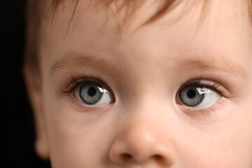 Naklejka premium Cute child with beautiful eyes on black background, closeup