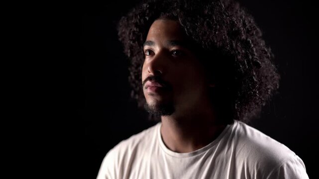 Young man with afro hair in a dark room suddenly seeing something that scares him