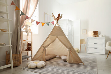 Stylish toy wigwam, furniture, pillows and decor in light playroom. Interior design © New Africa
