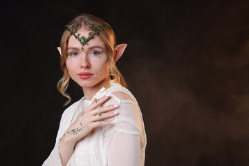 Obraz premium Beautiful elf girl on black background with smoke, space for text