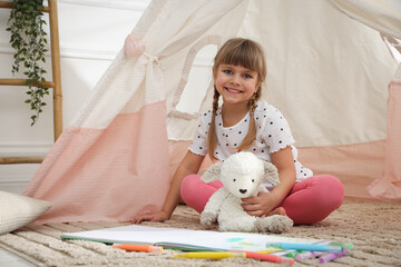 Little girl with toy sheep near wigwam at home © New Africa