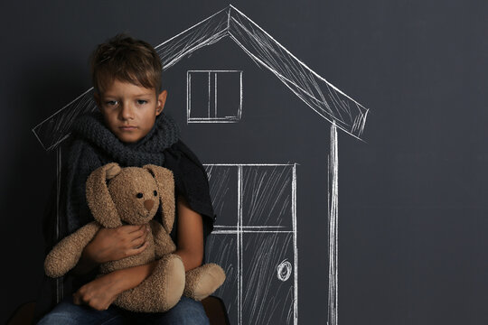 Homeless boy near wall with drawing of house. Dreaming about dwelling