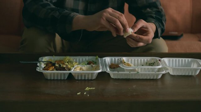 Man finishing takeaway food on the sofa at home