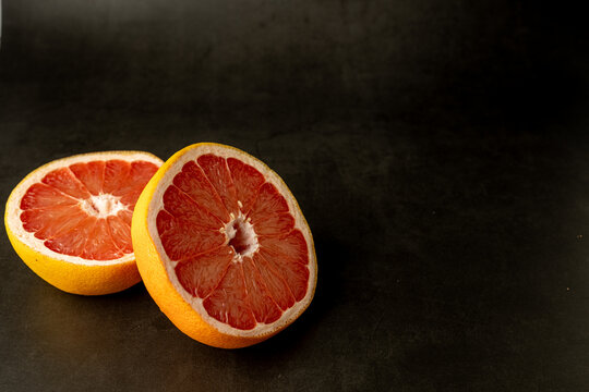 Grapefruit cut in half on a dark surface 