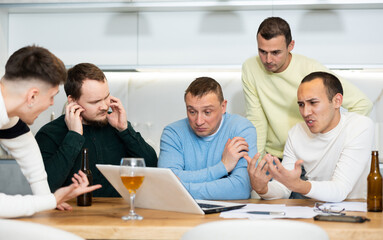 Fototapeta premium Men drink beer and try to help friend solve problems using laptop and the Internet