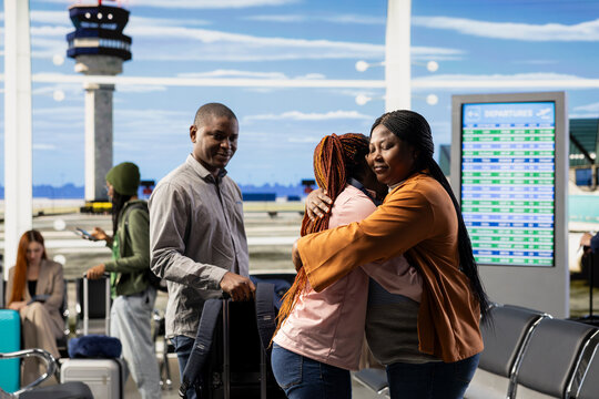 Emotional airport farewell with parents saying goodbye to teen daughter, child leaving to study abroad at university. Young traveler with luggage and passport prepares to airplane alone.