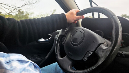 Driver hands on steering wheel inside car interior for safe driving tutorial and website banner...