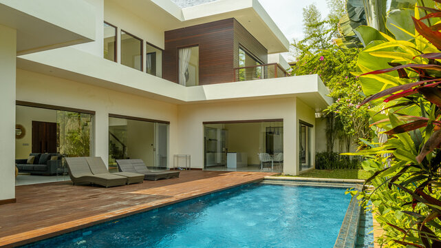 A large house with a pool and a garden. The house is white and has a lot of windows